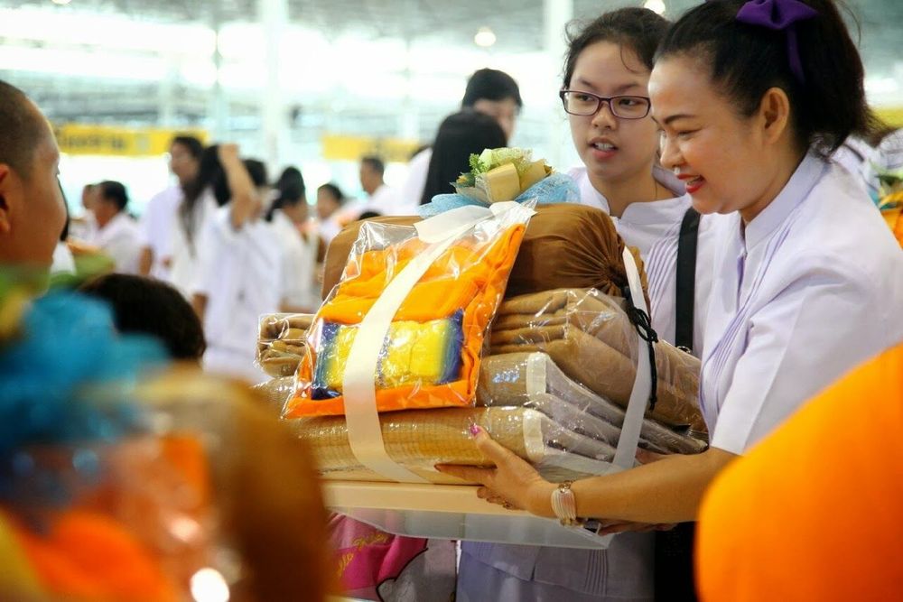 หญิงสาวในชุดขาวกำลังถือชุดเครื่องกันหนาวเพื่อเตรียมถวายแด่พระภิกษุสามเณร