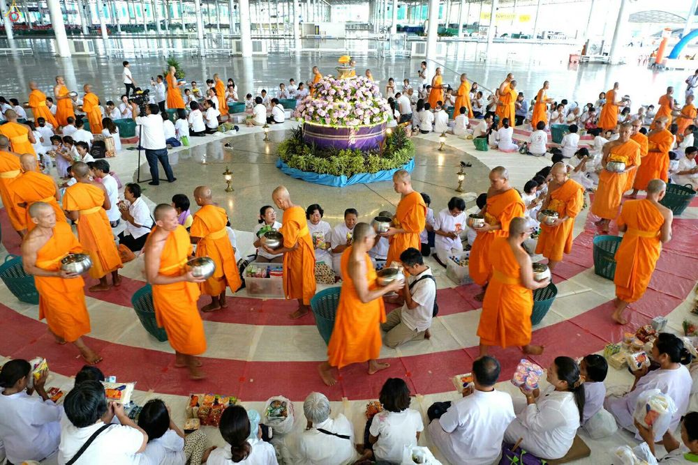 พุทธศาสนิกชนกำลังใส่บาตรพระภิกษุสงฆ์ในพิธีฉลองพระใหม่ภายในอาคาร