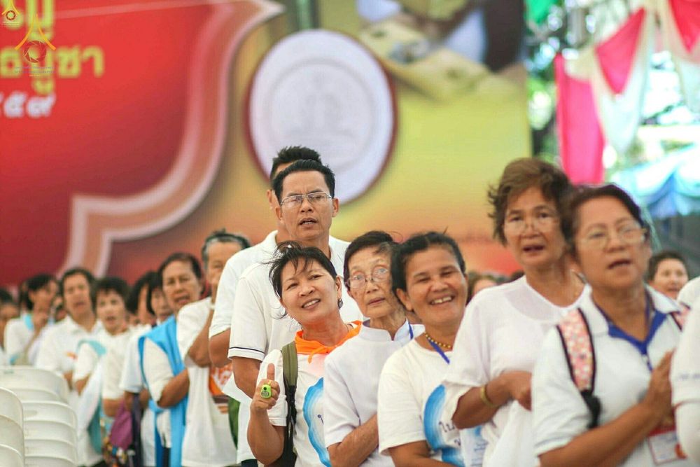 กลุ่มพุทธศาสนิกชนสวมชุดขาวเข้าแถวรอร่วมพิธีพิมพ์พระของขวัญรุ่นบรรลุธรรม