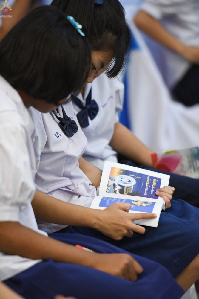 นักเรียนหญิงสองคนกำลังอ่านหนังสือในพิธีมอบรางวัลโครงการรักษาศีล 5
