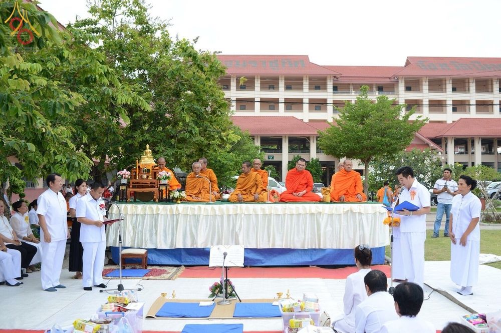 พระสงฆ์นั่งบนอาสนะในพิธีตักบาตรท่ามกลางพุทธศาสนิกชนที่แต่งกายด้วยชุดขาว ณ โรงเรียนเบญจมราชูทิศ จังหวัดปัตตานี