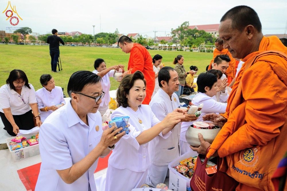 กลุ่มพุทธศาสนิกชนสวมชุดขาวกำลังใส่บาตรพระสงฆ์ในพิธีตักบาตร ณ โรงเรียนเบญจมราชูทิศ จังหวัดปัตตานี