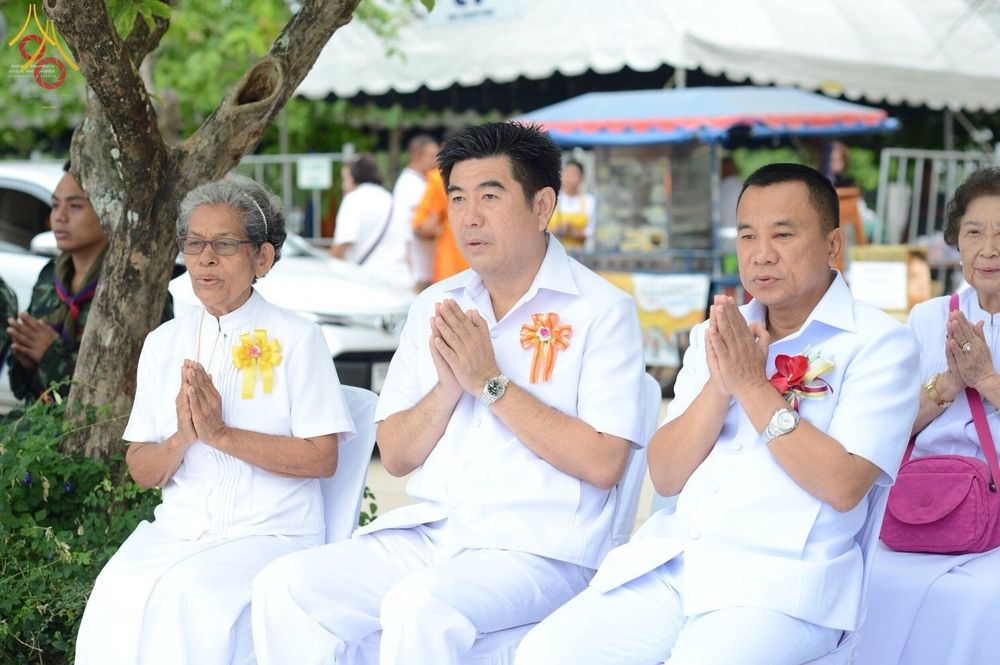 กลุ่มพุทธศาสนิกชนในชุดขาวนั่งพนมมือร่วมพิธีตักบาตรพระสงฆ์ 323 วัด 4 จังหวัดชายแดนภาคใต้ ณ โรงเรียนเบญจมราชูทิศ จังหวัดปัตตานี