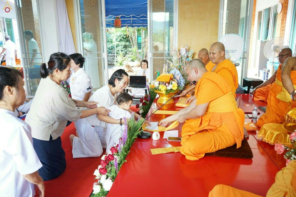 พุทธศาสนิกชนแต่งกายชุดขาวกำลังถวายปัจจัยแด่พระภิกษุสงฆ์ในพิธีทอดกฐินมหาสามัคคี ณ ธุดงคสถานลำพูน