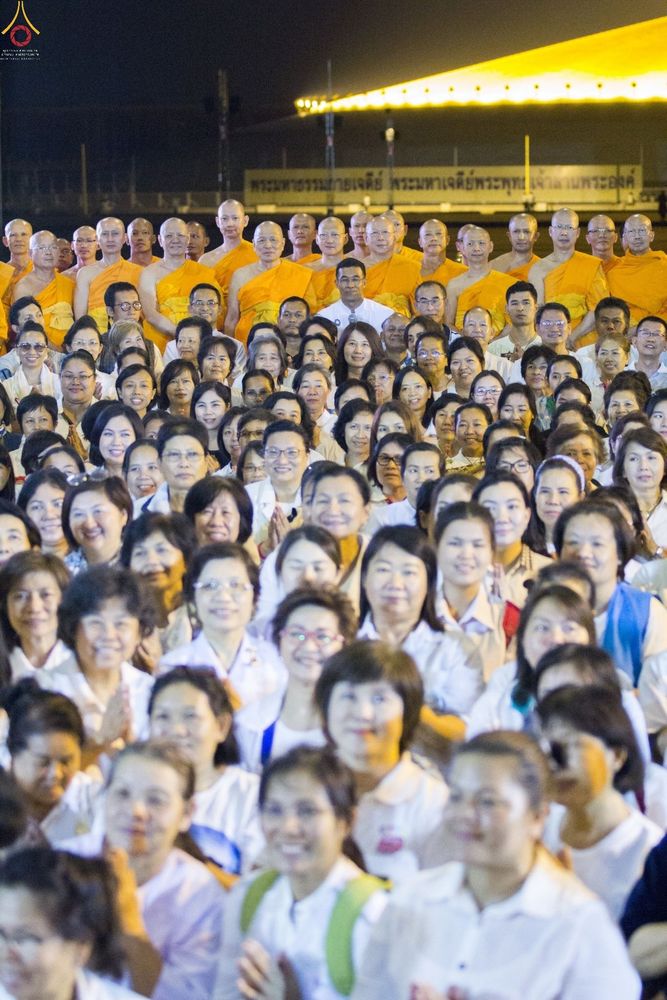กลุ่มพุทธศาสนิกชนและพระภิกษุสงฆ์จำนวนมากกำลังร่วมพิธีสวดมนต์ในยามค่ำคืน