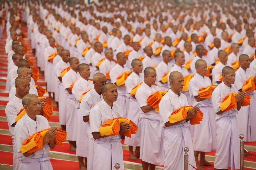 กลุ่มชายไทยในชุดขาวถือผ้าไตรจีวรสีเหลืองเตรียมเข้าพิธีบรรพชาในโครงการธรรมทายาท 1 แสนรูป