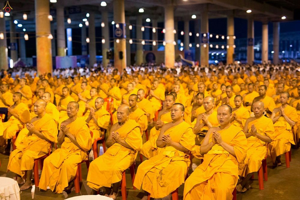 พระภิกษุสงฆ์จำนวนมากนั่งพนมมือสวดมนต์ในพิธีทางศาสนา