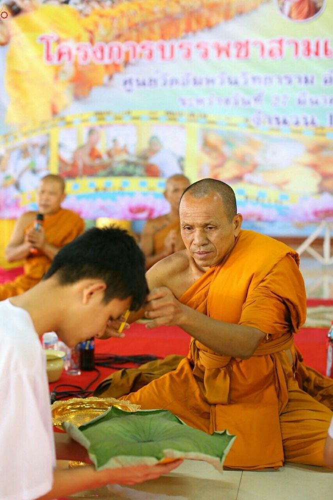 พระสงฆ์กำลังตัดปอยผมให้นาคในพิธีบรรพชาสามเณร