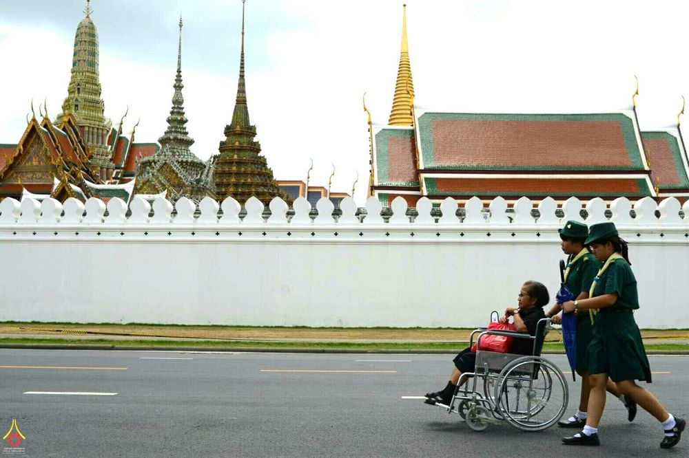 ลูกเสือหญิงช่วยเข็นรถเข็นผู้สูงอายุบริเวณหน้ากำแพงพระบรมมหาราชวัง