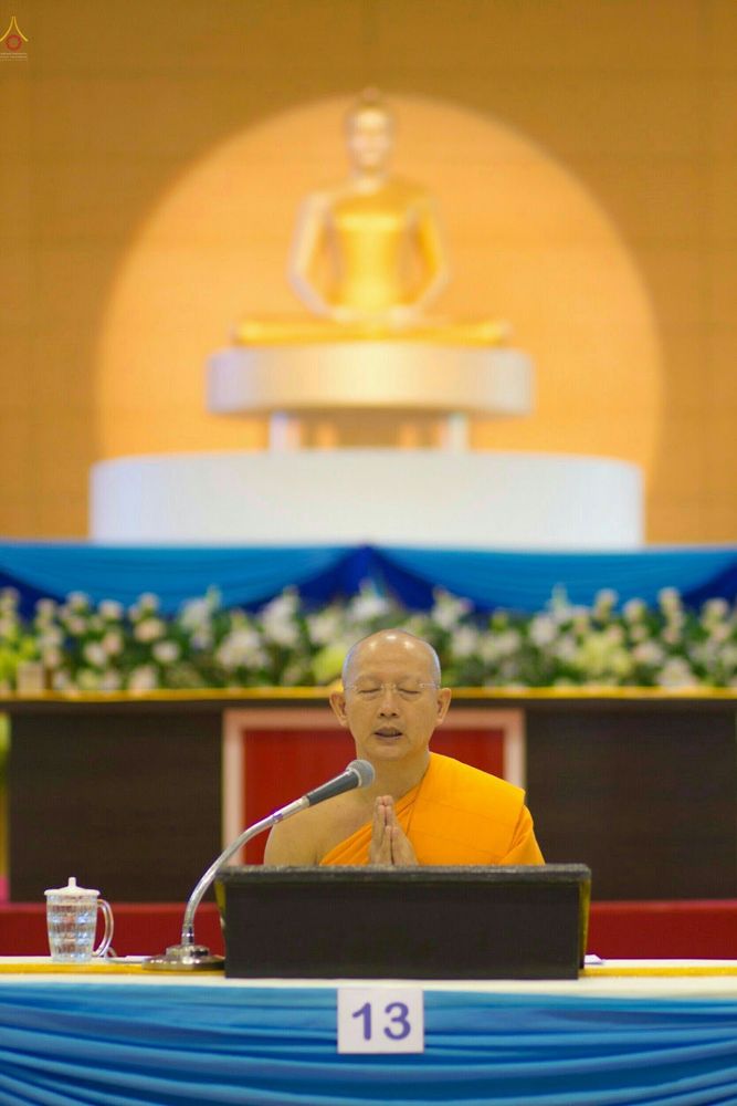พระภิกษุสงฆ์กำลังประนมมือสวดมนต์โดยมีพระพุทธรูปเป็นฉากหลัง