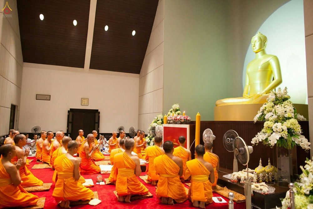 พระภิกษุสงฆ์นั่งสมาธิประกอบศาสนกิจเบื้องหน้าพระพุทธรูปในพิธีบรรพชาอุปสมบทหมู่