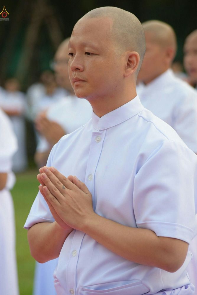 นาคธรรมทายาทชายโกนศีรษะสวมชุดขาวพนมมือด้วยอาการสำรวมในพิธีบรรพชาอุปสมบทหมู่