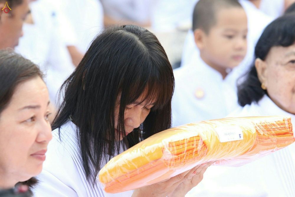 หญิงไทยสวมชุดขาวถือผ้าไตรจีวรในพิธีบรรพชาอุปสมบทหมู่