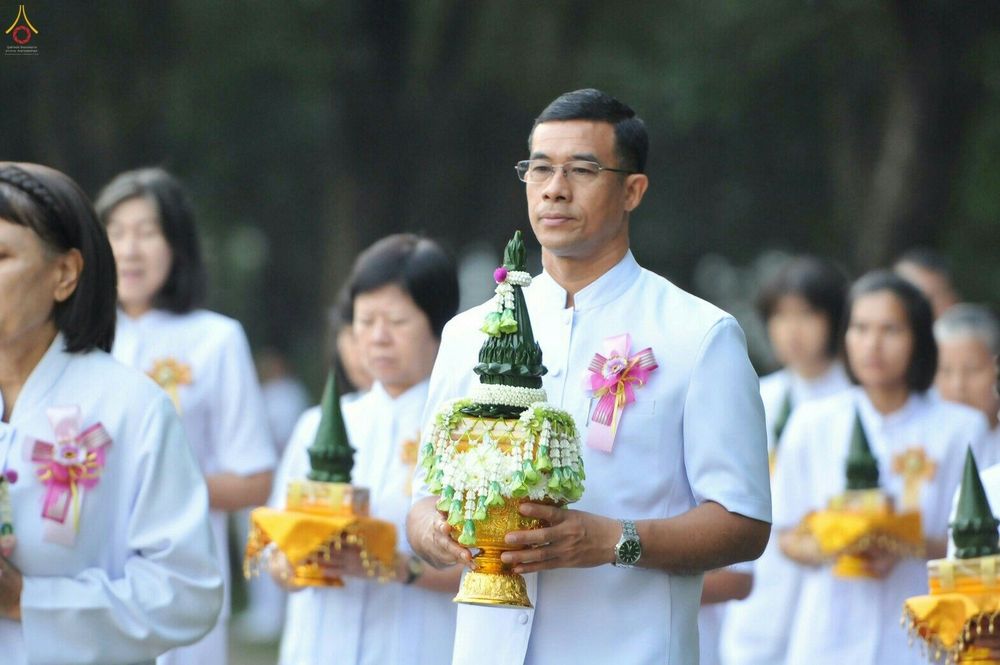 ชายสวมชุดขาวถือพานพุ่มดอกไม้ในพิธีบรรพชาอุปสมบทหมู่นาคธรรมทายาท
