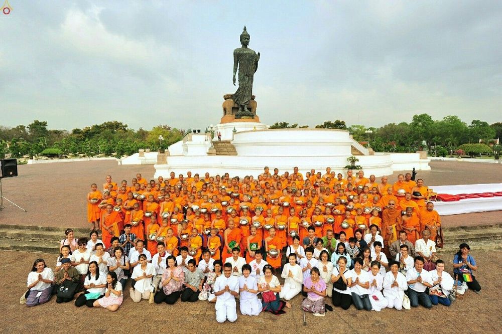กลุ่มสามเณรและพุทธศาสนิกชนจำนวนมากนั่งและยืนถ่ายภาพร่วมกันหน้าองค์พระประธานพุทธมณฑล