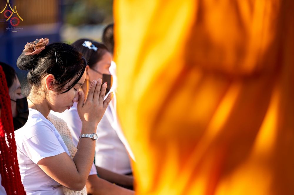 หญิงสาวสวมชุดขาวพนมมือไหว้ด้วยความศรัทธาในพิธีต้อนรับพระธรรมยาตรา