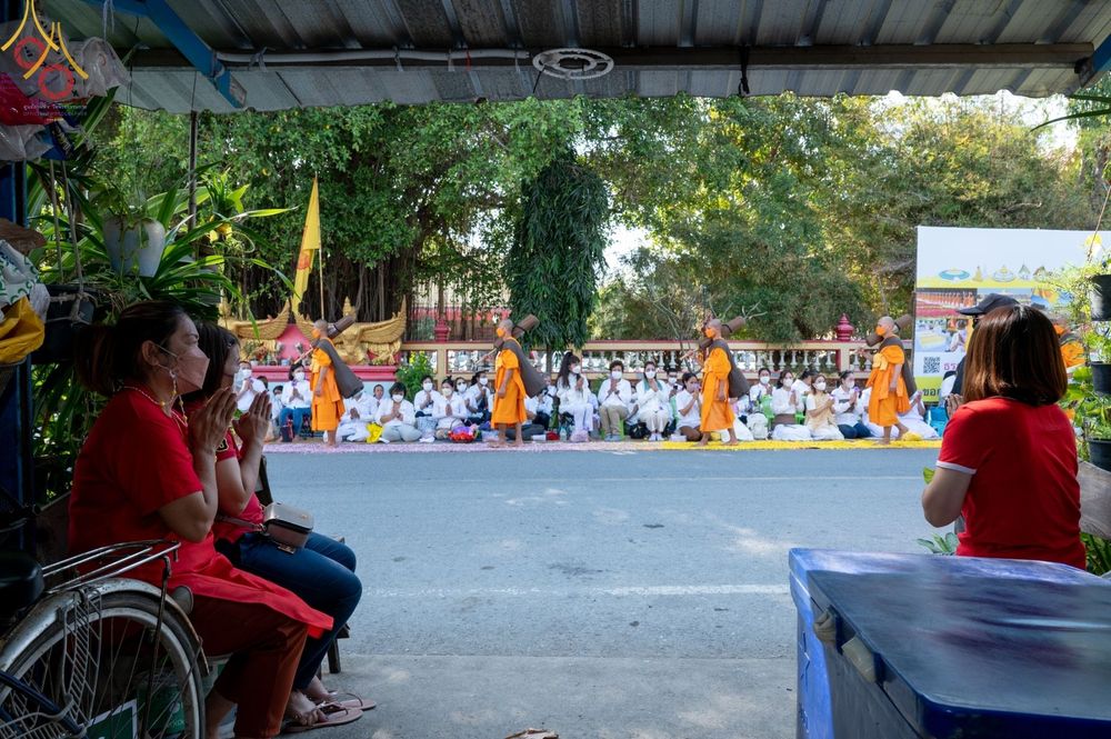 คณะพระภิกษุสงฆ์เดินธุดงค์ผ่านพุทธศาสนิกชนที่นั่งพนมมือต้อนรับบริเวณหน้าวัดบางปลา