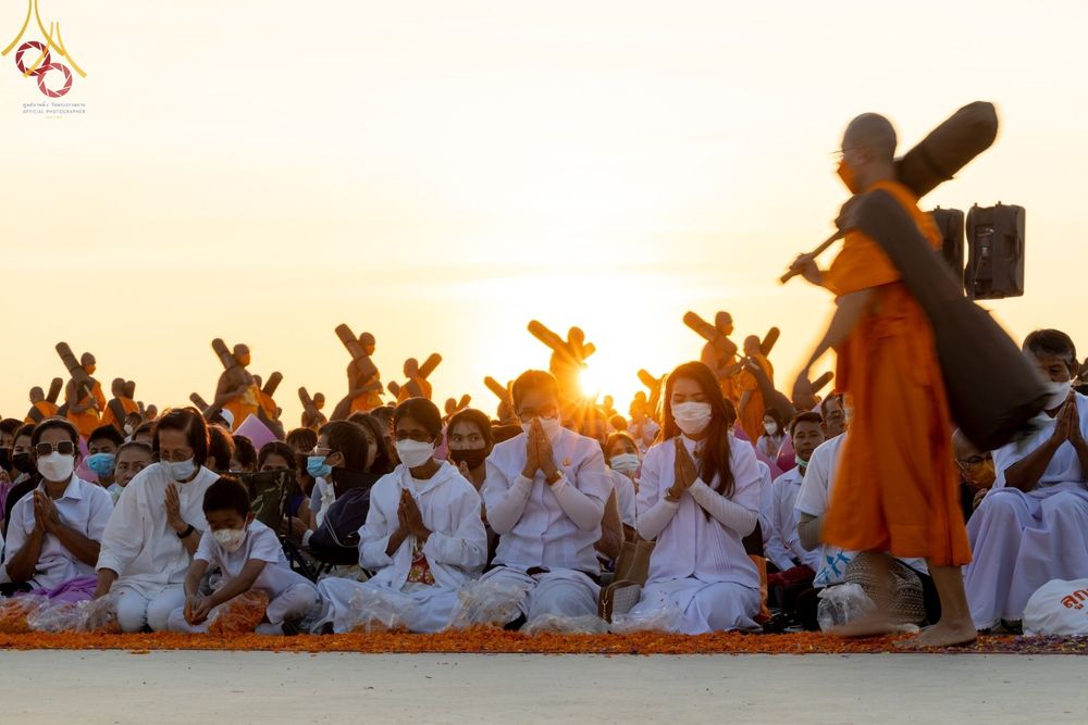 พุทธศาสนิกชนนั่งพนมมือต้อนรับพระธรรมยาตราท่ามกลางแสงอาทิตย์ยามเย็นที่วัดบางปลา