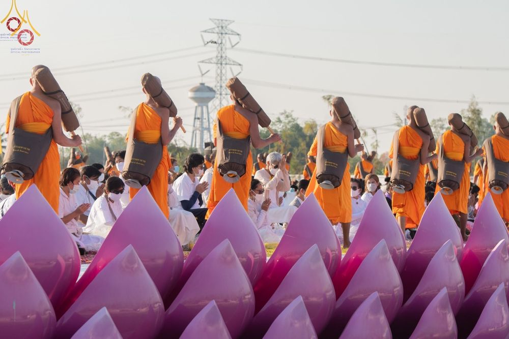 คณะพระภิกษุสงฆ์เดินธุดงค์ในโครงการธรรมยาตรากตัญญูบูชาท่ามกลางพุทธศาสนิกชนและดอกบัวประดับ