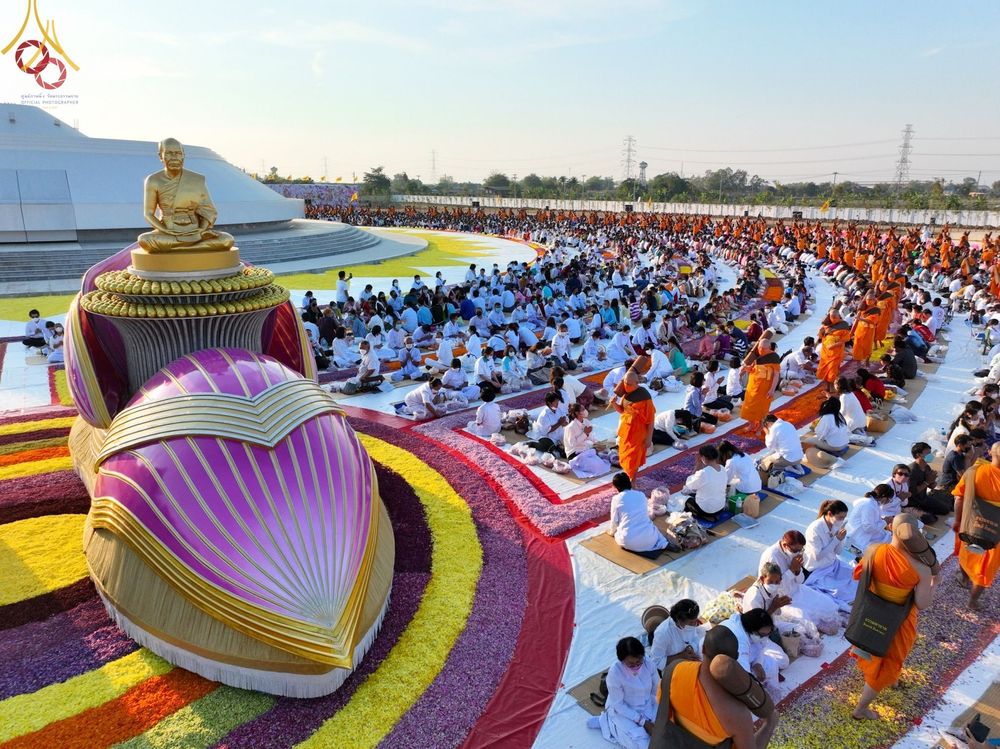 พระภิกษุสงฆ์และพุทธศาสนิกชนชุดขาวร่วมพิธีต้อนรับพระธรรมยาตรา บริเวณลานอนุสรณ์สถานบางปลาที่มีการประดับตกแต่งด้วยดอกไม้อย่างสวยงาม