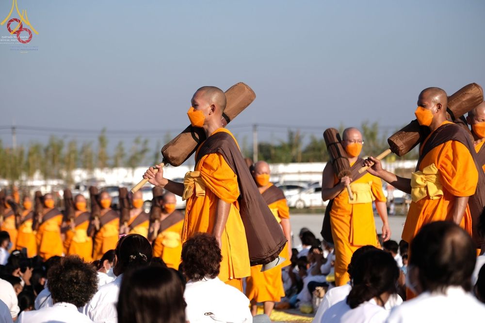 คณะพระธรรมยาตราสวมจีวรสีเหลืองทองและหน้ากากอนามัยสีส้ม เดินแถวถือกลดในพิธีต้อนรับโครงการธรรมยาตรากตัญญูบูชา