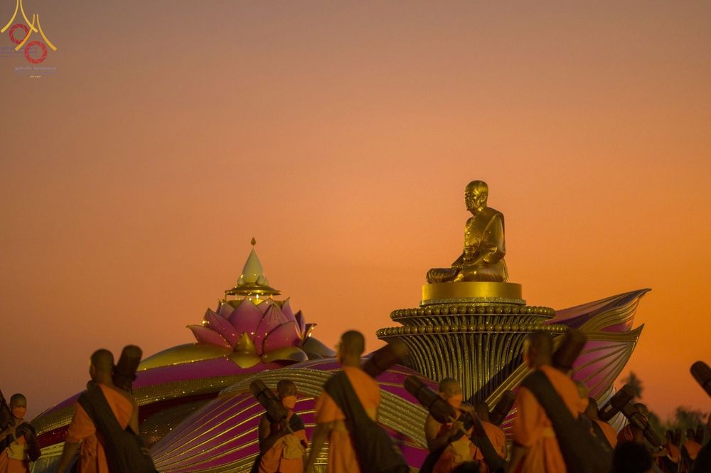 คณะพระธรรมยาตราเดินผ่านรูปหล่อทองคำพระมงคลเทพมุนี (สด จนฺทสโร) ท่ามกลางแสงอาทิตย์ยามเย็นที่อนุสรณ์สถานบางปลา