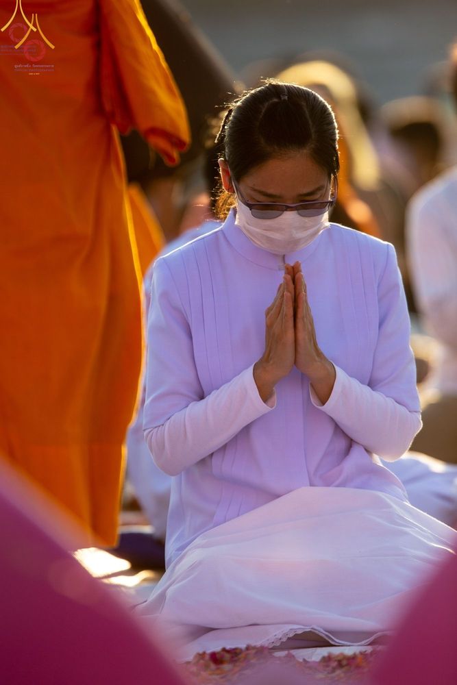 หญิงสวมชุดขาวพนมมือในพิธีต้อนรับพระธรรมยาตรา