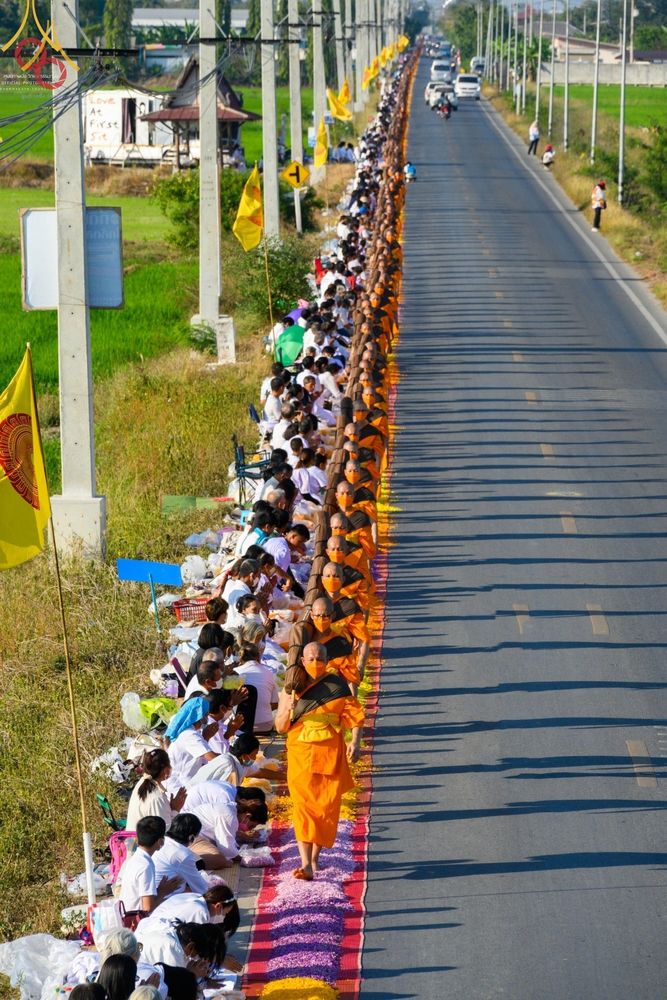 คณะพระภิกษุสงฆ์เดินธุดงค์บนเส้นทางที่ปูด้วยกลีบดอกไม้ท่ามกลางพุทธศาสนิกชนที่มารอรับ