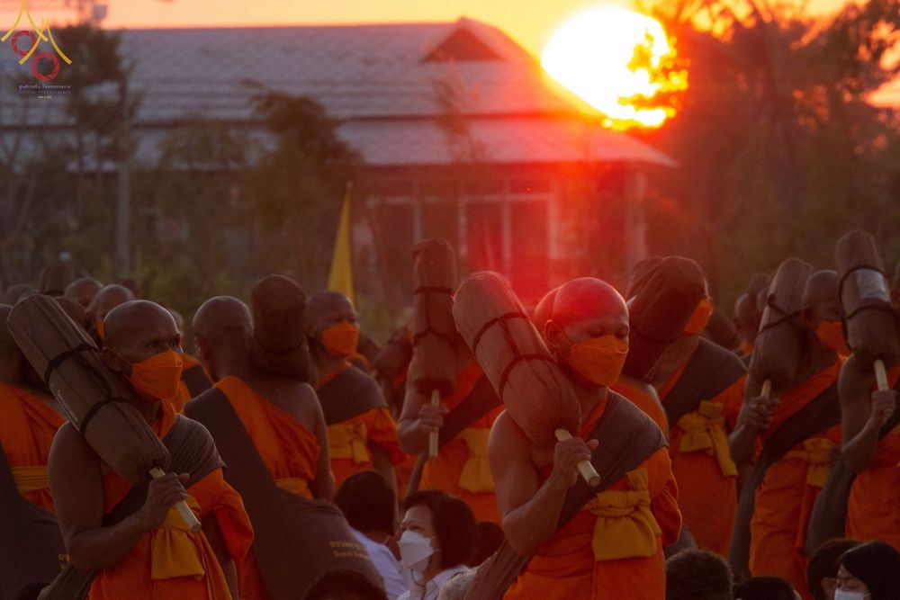 คณะพระธรรมยาตราสวมหน้ากากอนามัยแบกกลดเดินธุดงค์ท่ามกลางแสงอาทิตย์ยามเย็น ณ อนุสรณ์สถานบางปลา
