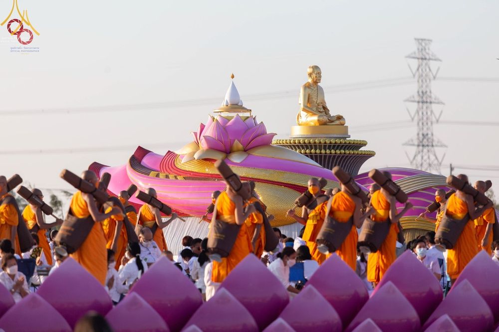 คณะพระธรรมยาตราเดินแถวผ่านประติมากรรมดอกบัวและรูปหล่อทองคำพระมงคลเทพมุนีในโครงการธรรมยาตรากตัญญูบูชา