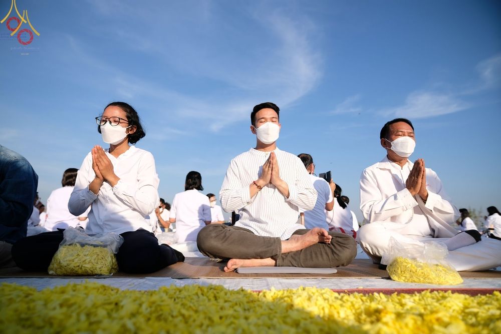 กลุ่มพุทธศาสนิกชนสวมชุดขาวนั่งสมาธิพนมมือในโครงการธรรมยาตรากตัญญูบูชา