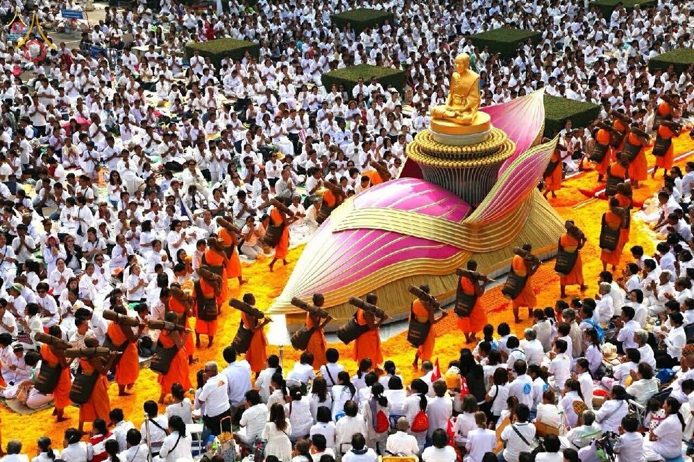 พระภิกษุสงฆ์เดินธุดงค์บนเส้นทางดอกดาวเรืองท่ามกลางพุทธศาสนิกชนชุดขาวจำนวนมาก