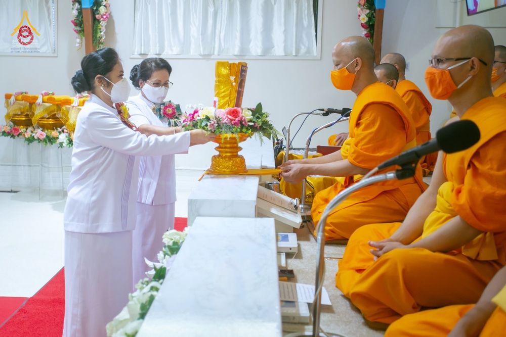 พุทธศาสนิกชนสวมชุดขาวถวายพานพุ่มดอกไม้แด่พระสงฆ์ในพิธีทอดกฐินสามัคคี