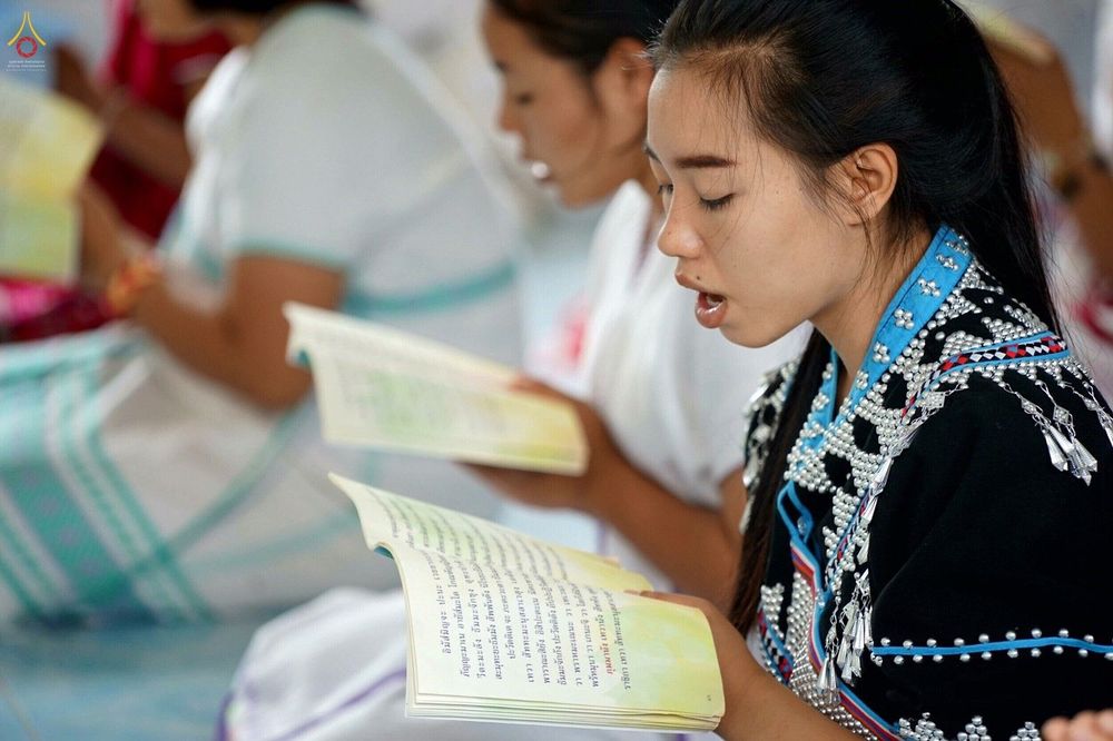 เยาวชนหญิงสวมชุดพื้นเมืองกำลังถือหนังสือสวดมนต์และตั้งใจสวดมนต์ในโครงการทำดีเพื่อพ่อ