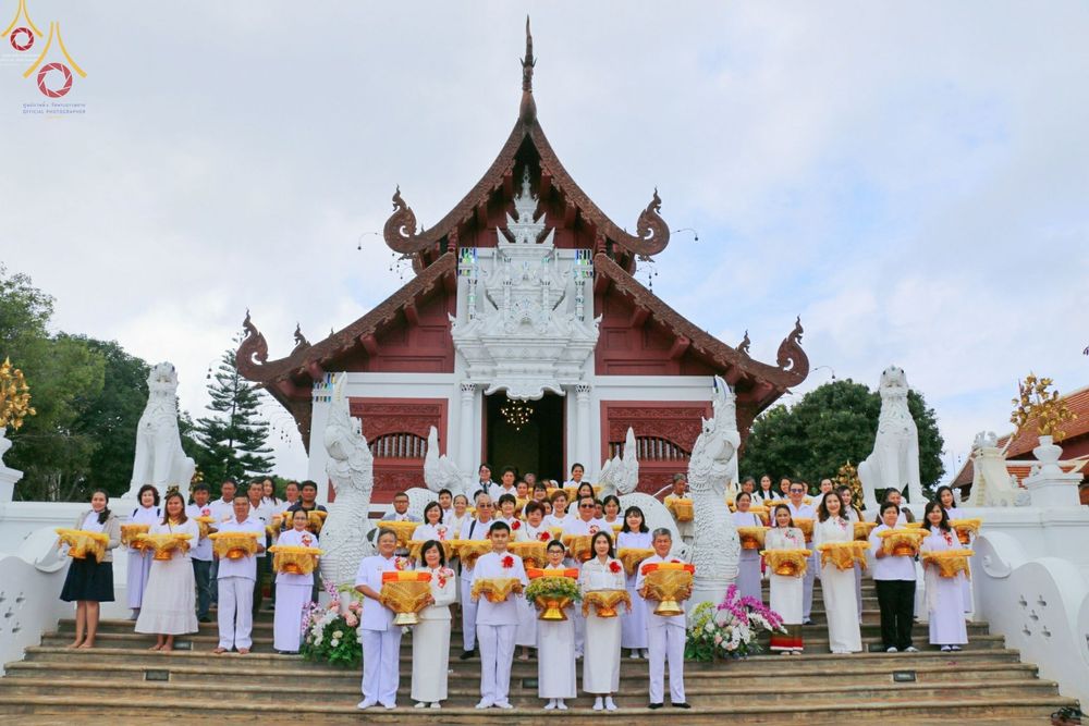 กลุ่มพุทธศาสนิกชนแต่งกายชุดสีขาวถือพานพุ่มยืนเรียงแถวบนบันไดหน้าพระวิหารวัดกิ่วลม จังหวัดเชียงใหม่ ในงานพิธีทอดกฐินสามัคคี