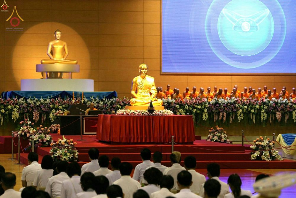 บรรยากาศพิธีบูชาครูผู้ค้นพบวิชชาธรรมกาย มีรูปหล่อทองคำประดิษฐานบนแท่นและคณะสงฆ์นั่งเรียงรายอยู่ด้านหลัง