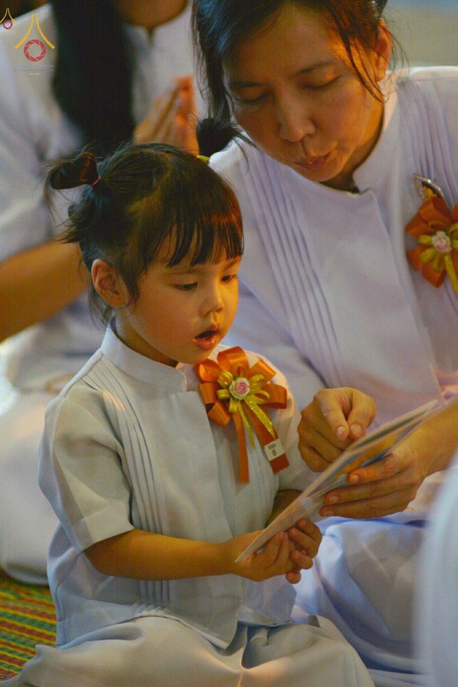 เด็กหญิงสวมชุดขาวกำลังอ่านหนังสือสวดมนต์ในงานวันครูผู้ค้นพบวิชชาธรรมกาย
