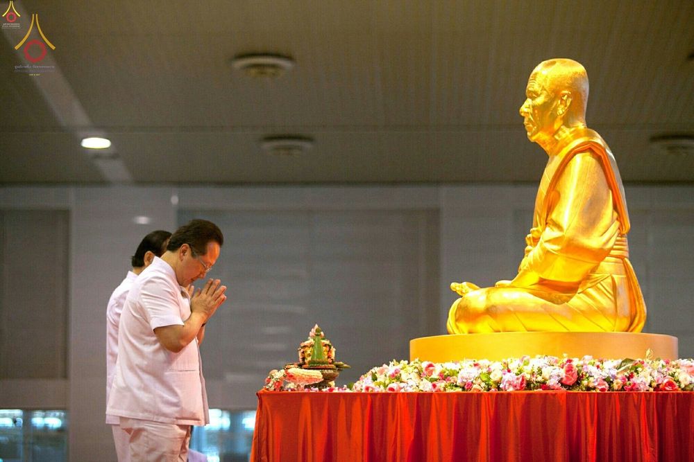 พุทธศาสนิกชนในชุดขาวกำลังกราบสักการะรูปหล่อทองคำพระมงคลเทพมุนี