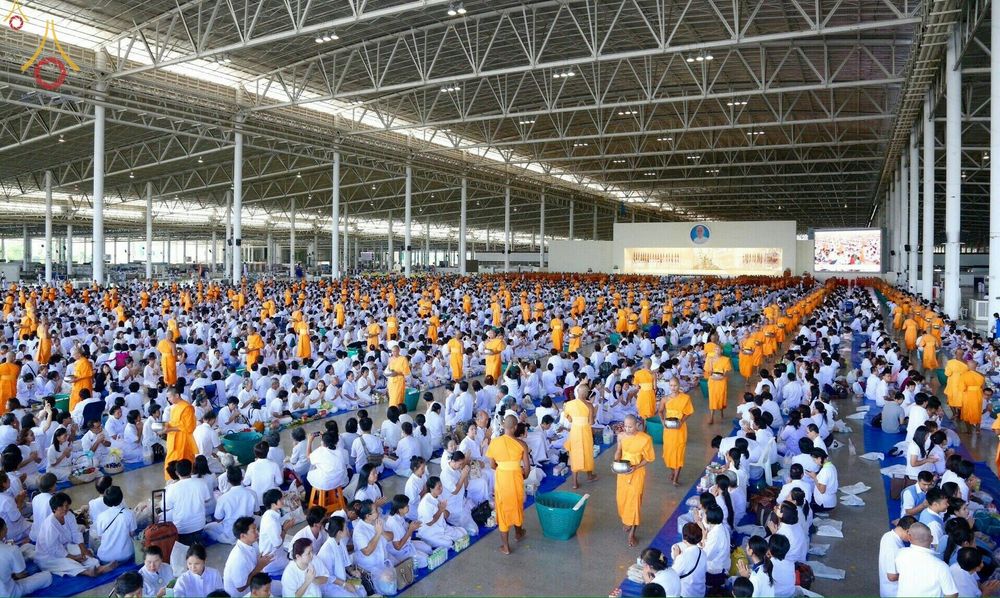 พุทธศาสนิกชนและพระภิกษุสงฆ์จำนวนมากร่วมพิธีตักบาตรภายในอาคารขนาดใหญ่ในวันครูผู้ค้นพบวิชชาธรรมกาย