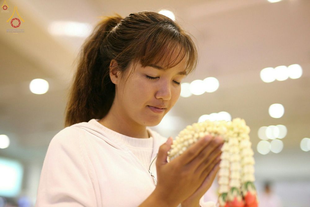 หญิงสาวพนมมือถือพวงมาลัยดอกมะลิด้วยความศรัทธาในงานบุญ