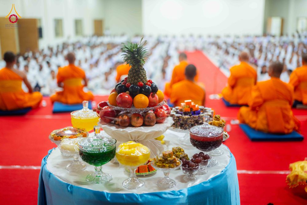โต๊ะวางผลไม้และเครื่องไทยธรรมตั้งอยู่หน้าแถวพระภิกษุสงฆ์และผู้เข้าร่วมพิธีที่นั่งอยู่บนพื้น