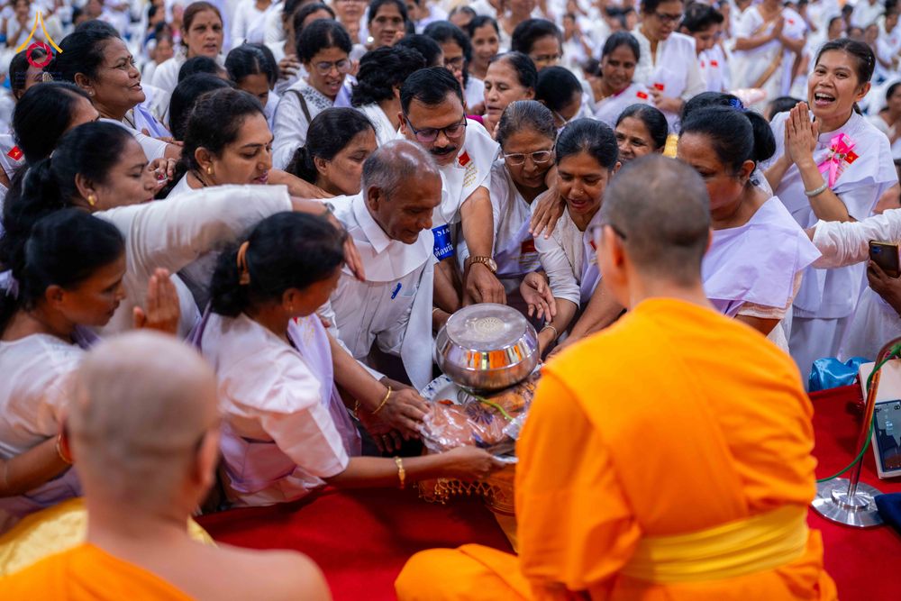 กลุ่มอุบาสกและอุบาสิกาในชุดขาวกำลังถวายบาตรแด่พระภิกษุสงฆ์ในพิธีทางศาสนา