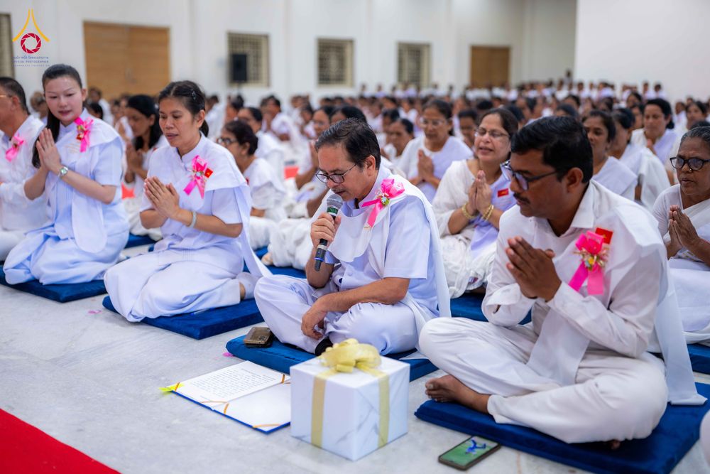 กลุ่มคนในชุดขาวนั่งพนมมือฟังการบรรยายในพิธีปิดโครงการอบรม