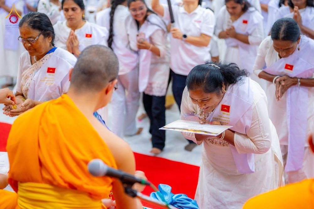 ผู้เข้าร่วมโครงการอบรมสวมชุดสีขาวก้มกราบรับเกียรติบัตรจากพระภิกษุสงฆ์