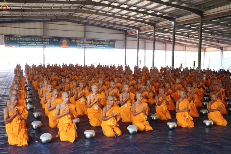 สามเณรจำนวนมากนั่งพนมมือเรียงแถวในพิธีบรรพชาสามเณรหมู่ภายในอาคาร