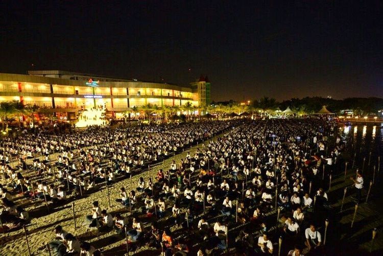 พุทธศาสนิกชนจำนวนมากนั่งสมาธิและประกอบพิธีทางศาสนาบนชายหาดในยามค่ำคืน ณ ชายหาดอันโคล กรุงจาการ์ตา