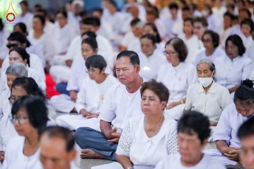 กลุ่มคนสวมชุดสีขาวนั่งสมาธิเรียงแถวกันอย่างเป็นระเบียบภายในอาคาร