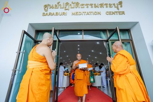 พระสงฆ์เดินออกจากประตูศูนย์ปฏิบัติธรรมสระบุรีโดยมีพระสงฆ์รูปอื่นยืนต้อนรับ
