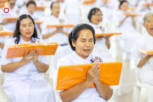 กลุ่มพุทธศาสนิกชนสวมชุดขาวถือผ้าไตรสีส้มประกอบพิธีทางศาสนา