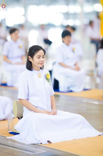 หญิงสาวสวมชุดขาวนั่งหลับตาทำสมาธิอย่างสงบในพื้นที่ปฏิบัติธรรม